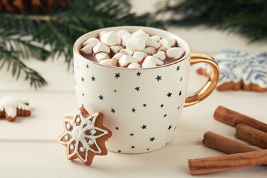 Delicious hot chocolate with marshmallows, gingerbread cookies and cinnamon on white wooden table, closeup