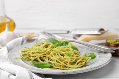 Delicious pasta with pesto sauce and basil on white table, closeup