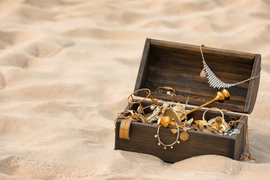 Open wooden treasure chest on sand, space for text