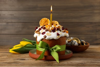 Tasty Easter cake with dried fruits, flowers and decorated eggs on wooden table