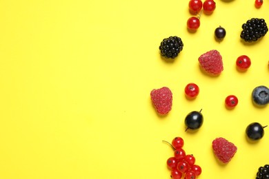 Photo of Mix of fresh berries on yellow background, flat lay. Space for text