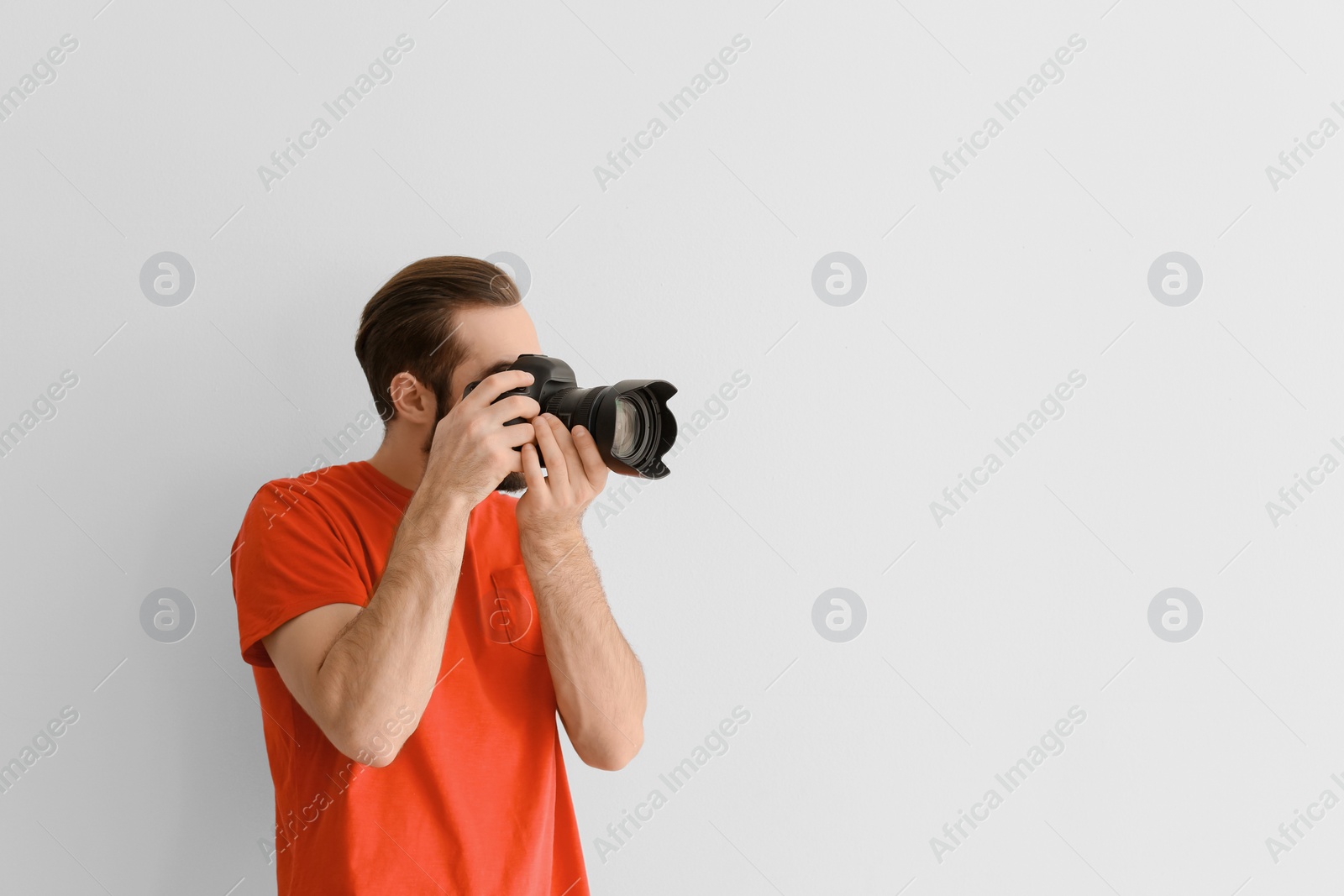 Photo of Young photographer with professional camera on white background