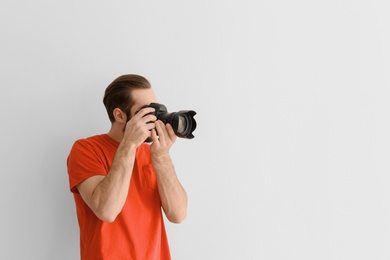 Photo of Young photographer with professional camera on white background