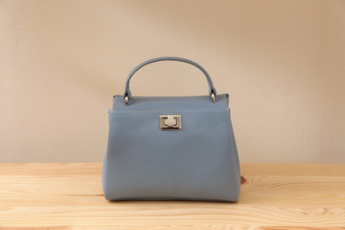 Photo of Stylish woman's bag on wooden table near beige wall