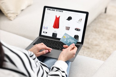 Woman with credit card using laptop for shopping online indoors, closeup