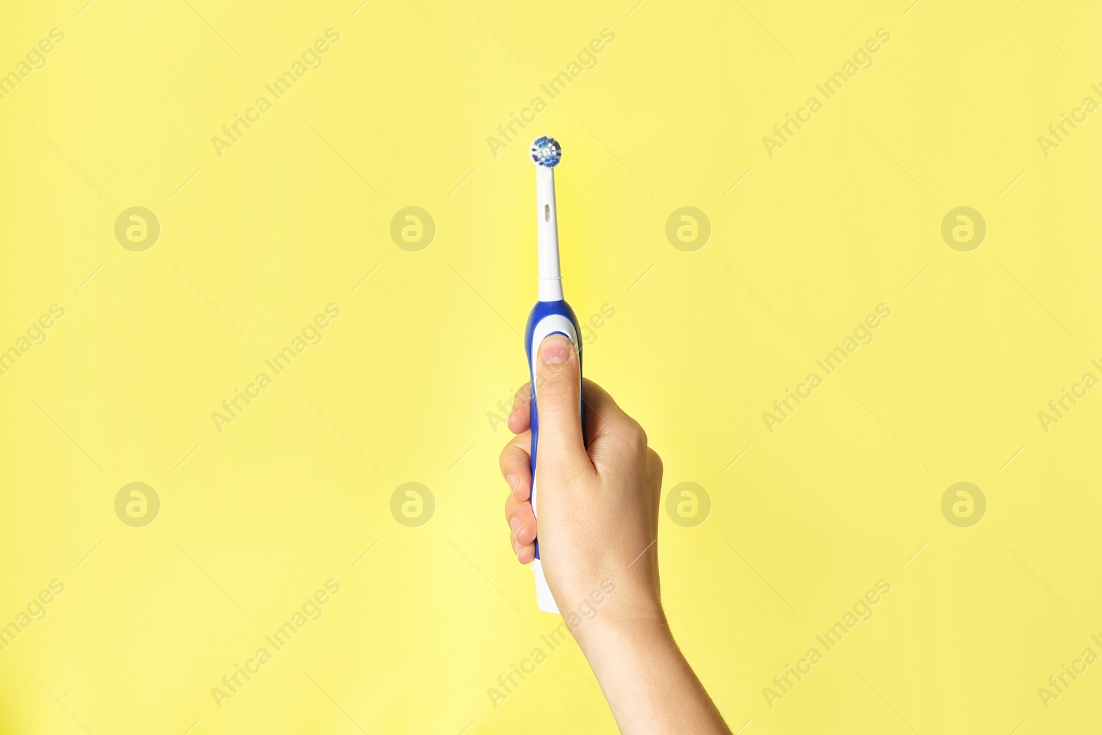 Photo of Woman holding electric toothbrush against color background