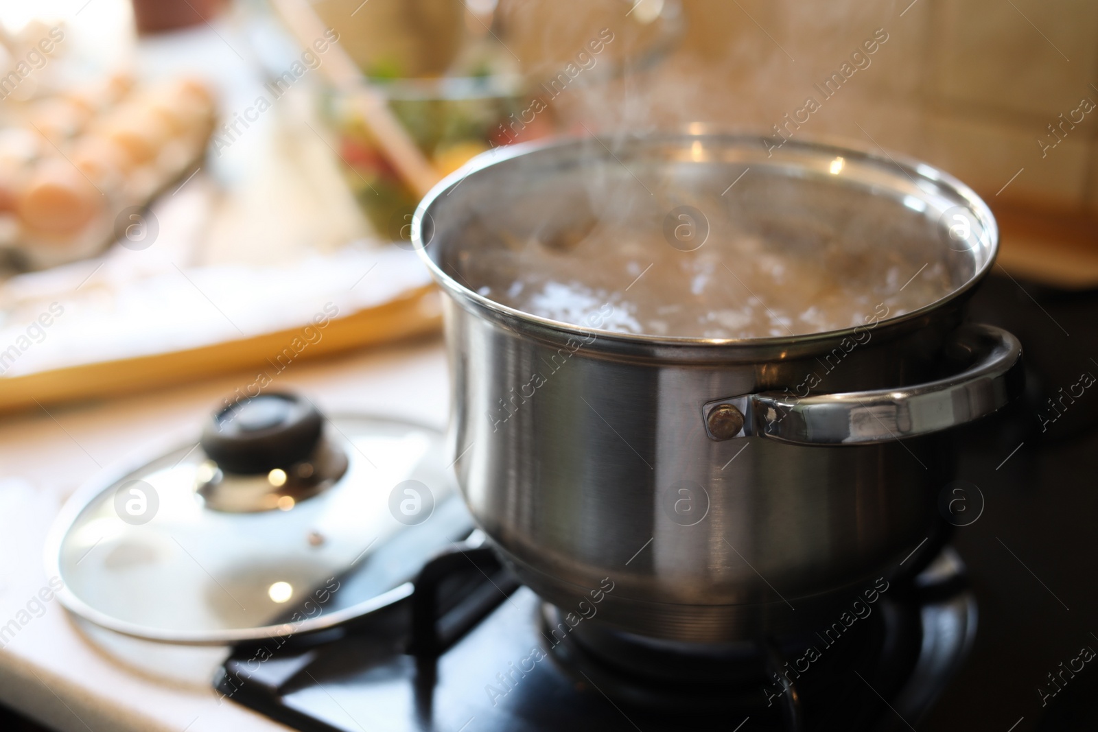 Photo of Shiny pot with boiling water on stove indoors. Space for text