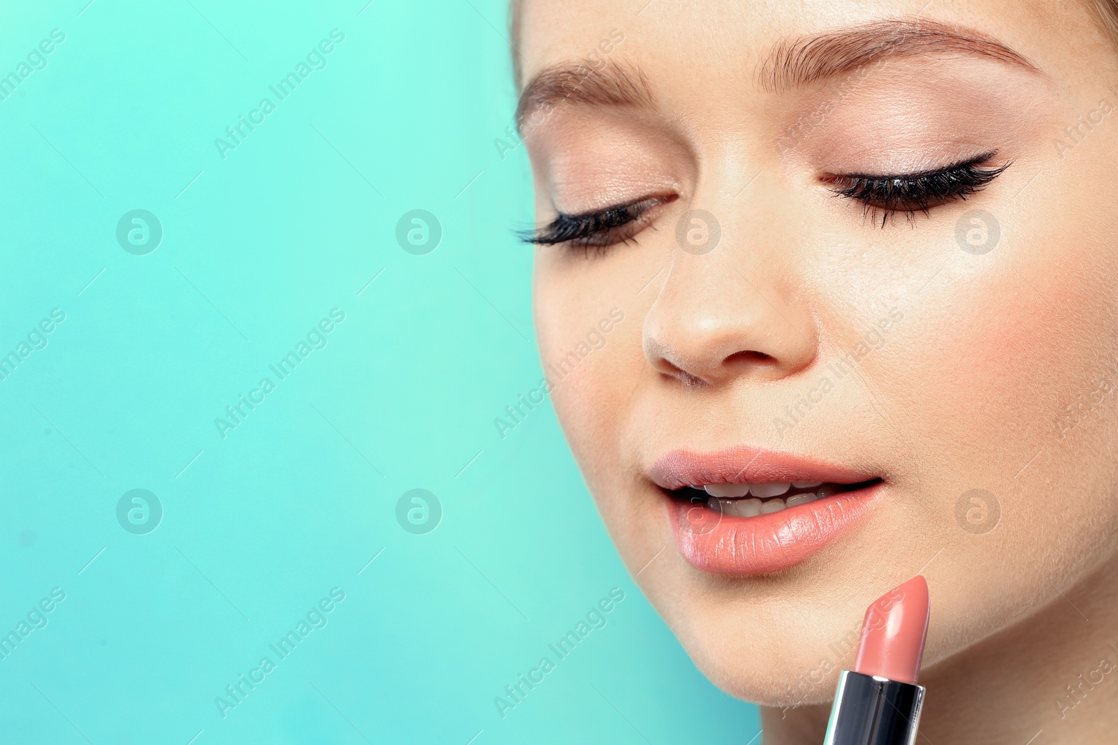 Photo of Beautiful woman applying nude lipstick on color background. Space for text