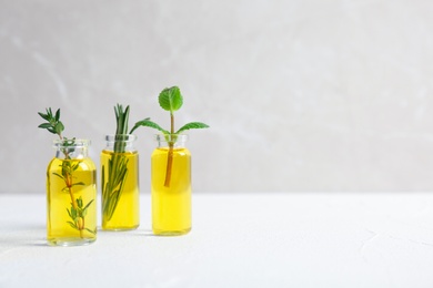 Photo of Bottles with essential oils and fresh herbs on light background