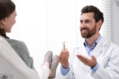 Photo of Doctor with educational model of dental implant consulting patient in clinic