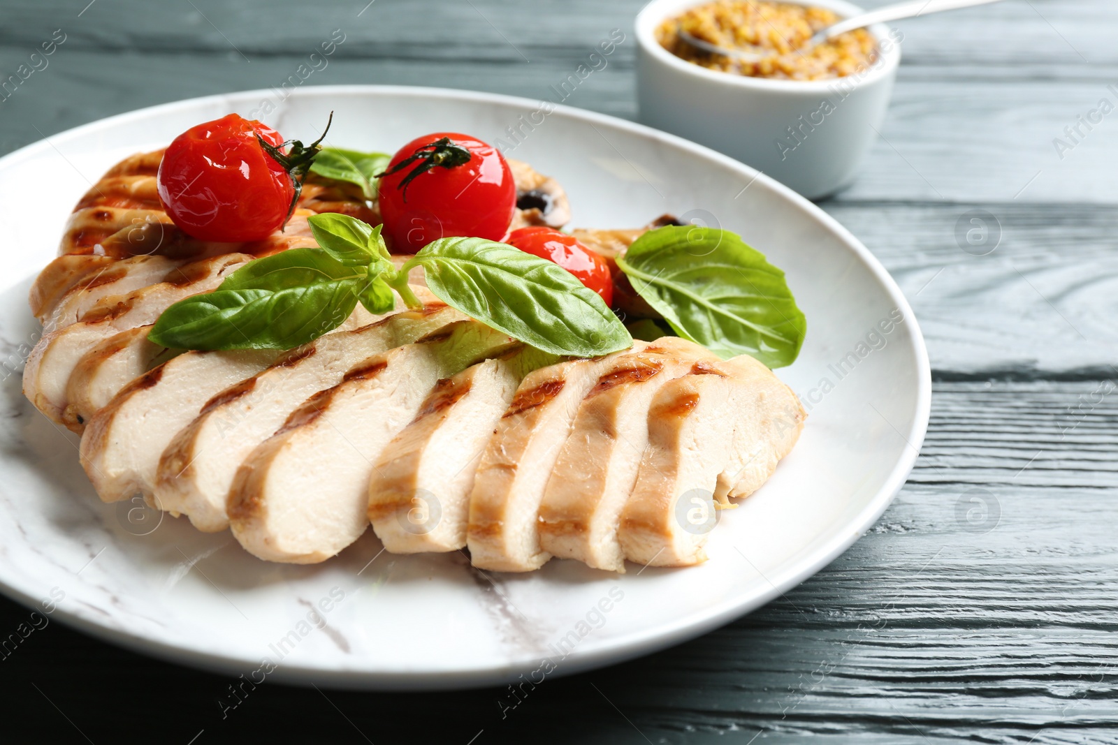 Photo of Tasty grilled chicken fillet with green basil and tomatoes on grey wooden table, closeup