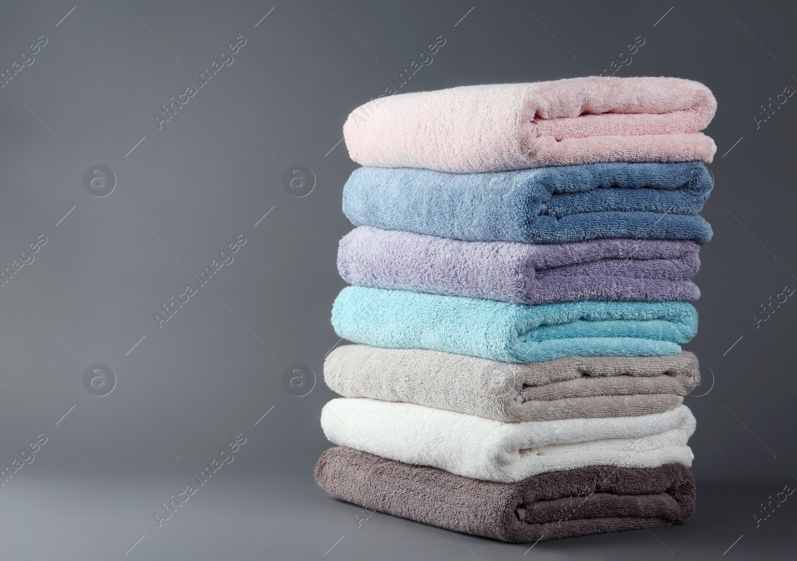 Photo of Different fresh soft terry towels on grey background