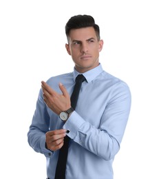 Photo of Handsome stylish man putting on cufflink against white background