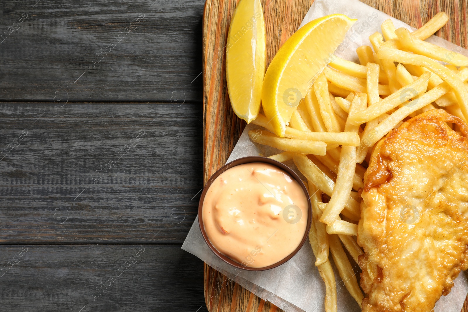 Photo of Board with British traditional fish and potato chips on wooden background, top view. Space for text