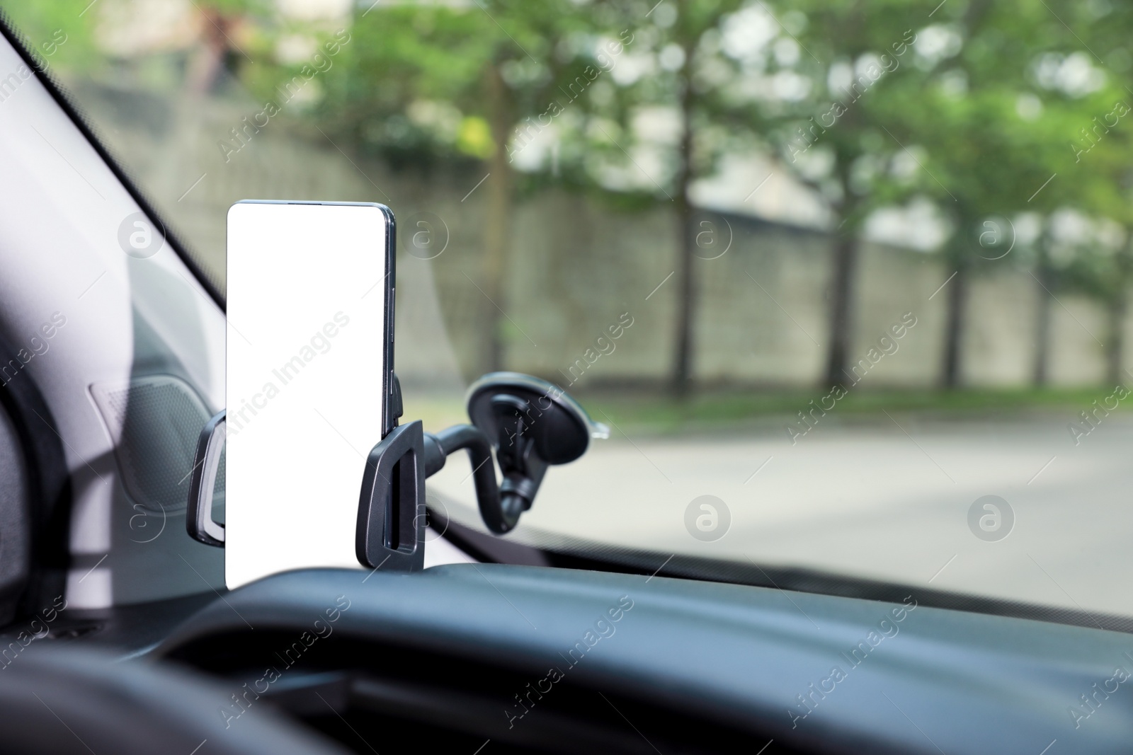 Photo of Car holder with modern mobile phone on windshield of automobile. Mockup for design