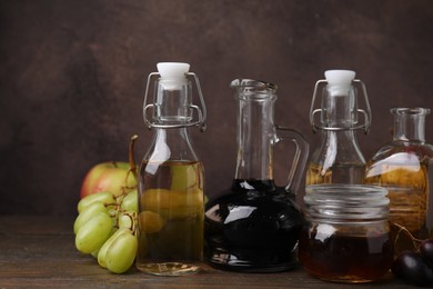 Photo of Different types of vinegar and fresh fruits on wooden table