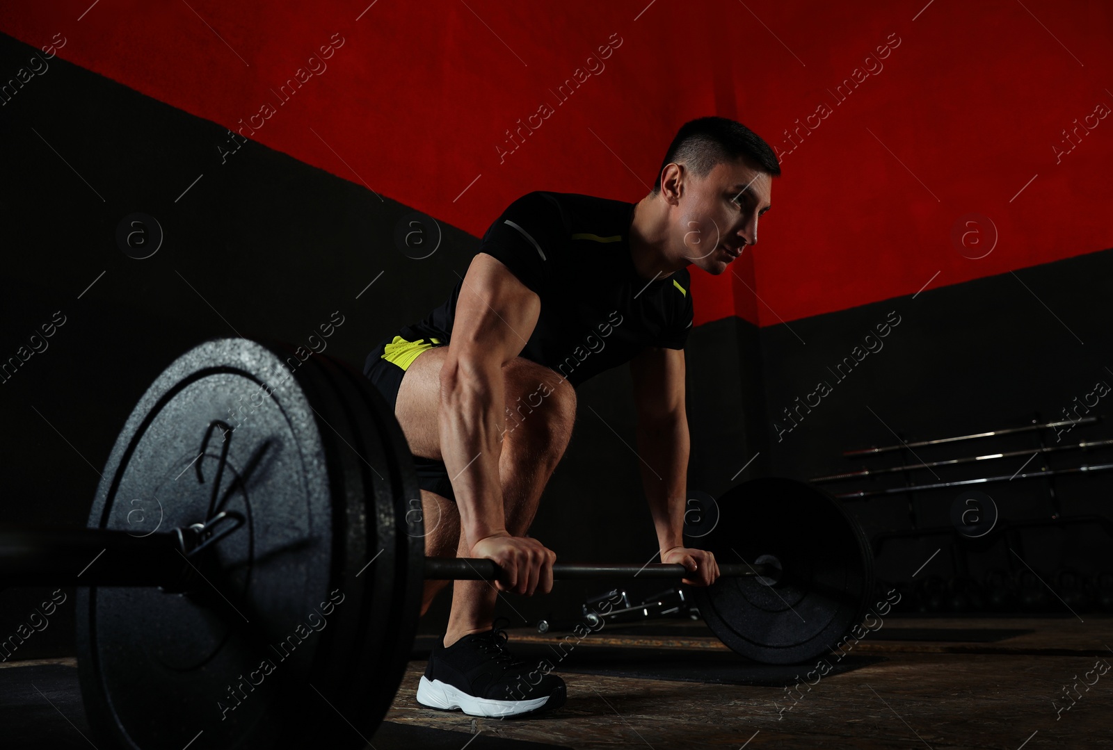 Photo of Strong man lifting barbell in modern gym