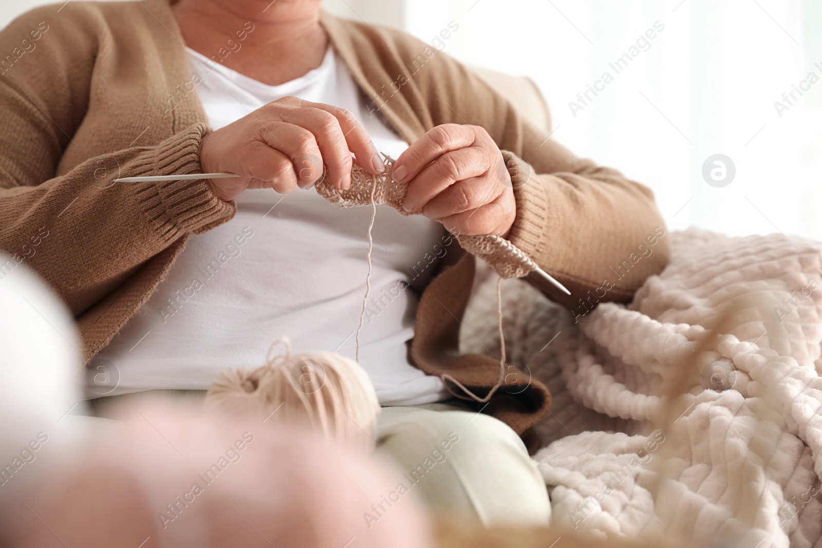 Photo of Elderly woman knitting at home, closeup. Creative hobby