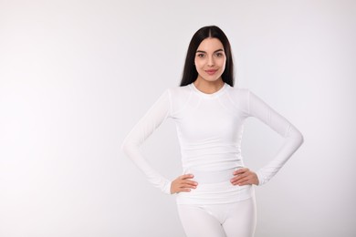 Woman in warm thermal underwear on light background. Space for text
