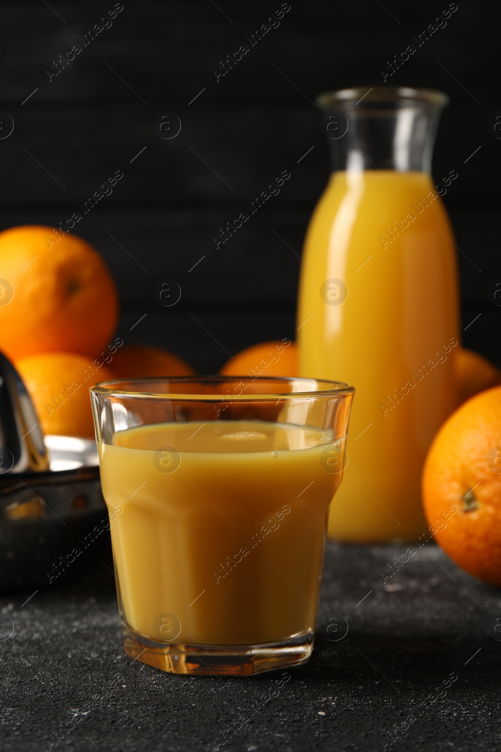 Photo of Tasty fresh oranges and juice on black table, closeup