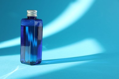 Photo of Bottle of cosmetic product on light blue background. Space for text