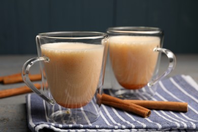 Photo of Delicious eggnog with cinnamon on grey wooden table