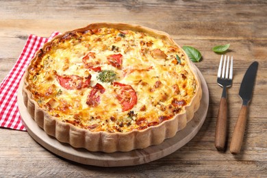 Photo of Tasty quiche with tomatoes and cheese served on wooden table, closeup