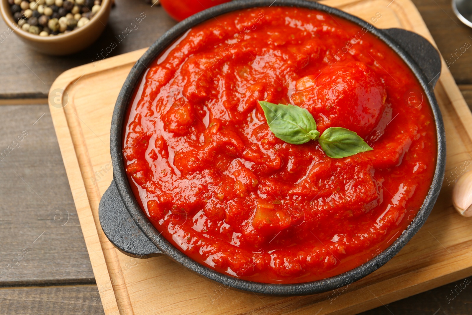 Photo of Homemade tomato sauce and basil in bowl on wooden table