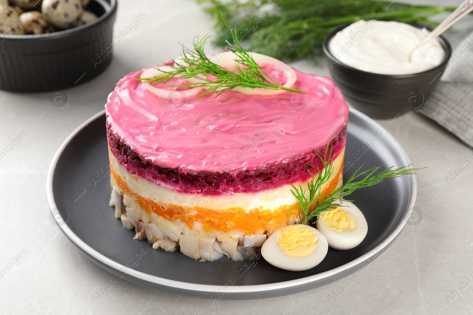 Photo of Herring under fur coat salad on light grey table. Traditional Russian dish