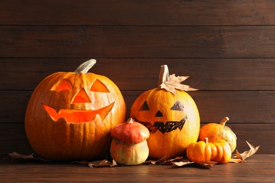 Photo of Halloween pumpkin head jack lanterns on table against wooden background