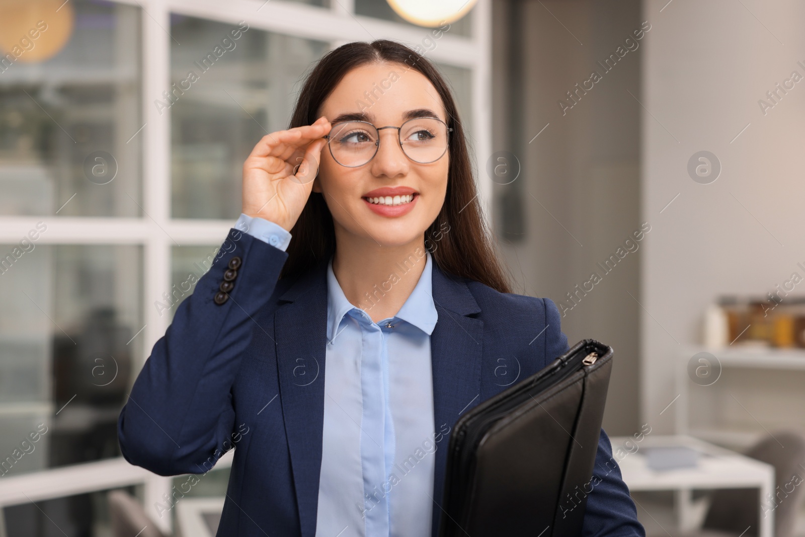 Photo of Happy real estate agent with leather portfolio in office