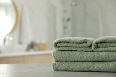 Photo of Stack of clean towels on table in bathroom. Space for text