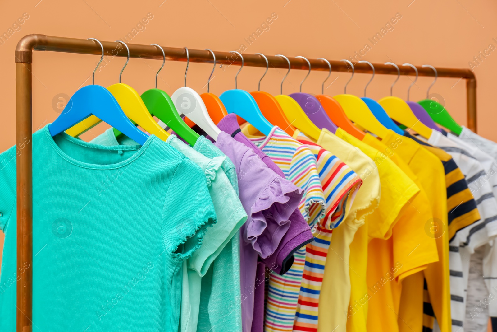 Photo of Rack with stylish children clothes on beige background, closeup