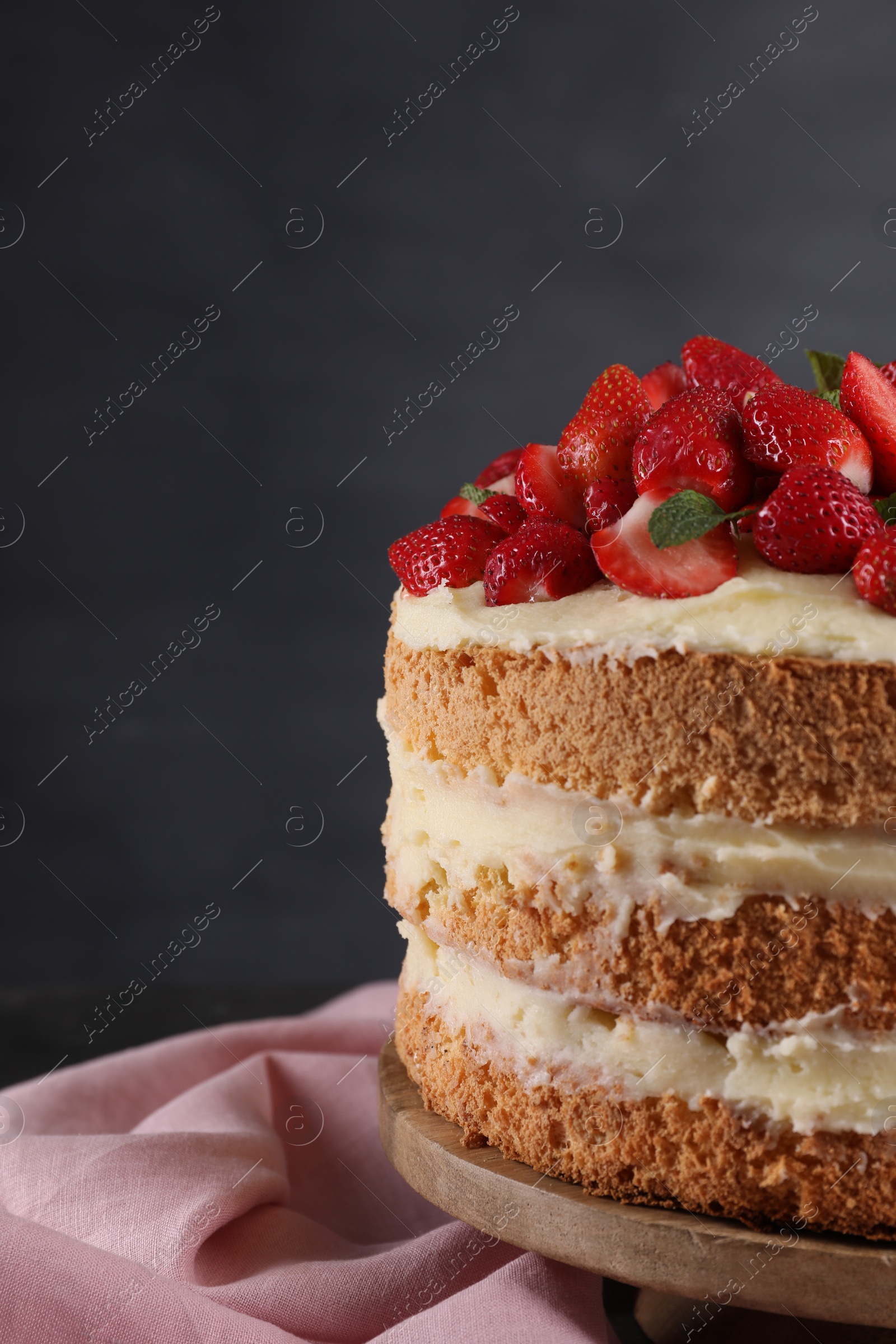 Photo of Tasty cake with fresh strawberries and mint on table against dark gray background