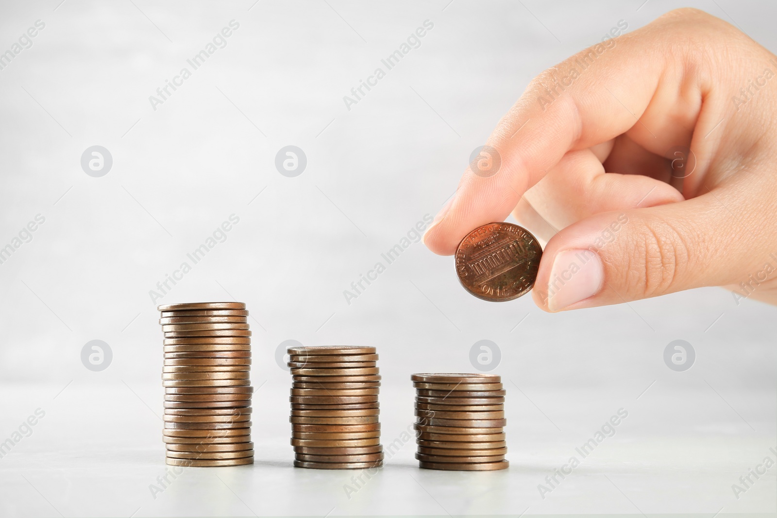 Photo of Woman stacking coins on grey stone table, closeup view