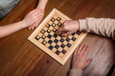 Man playing checkers with woman at wooden table, above view