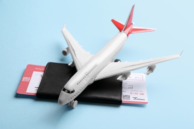 Toy airplane and passport with ticket on light blue background