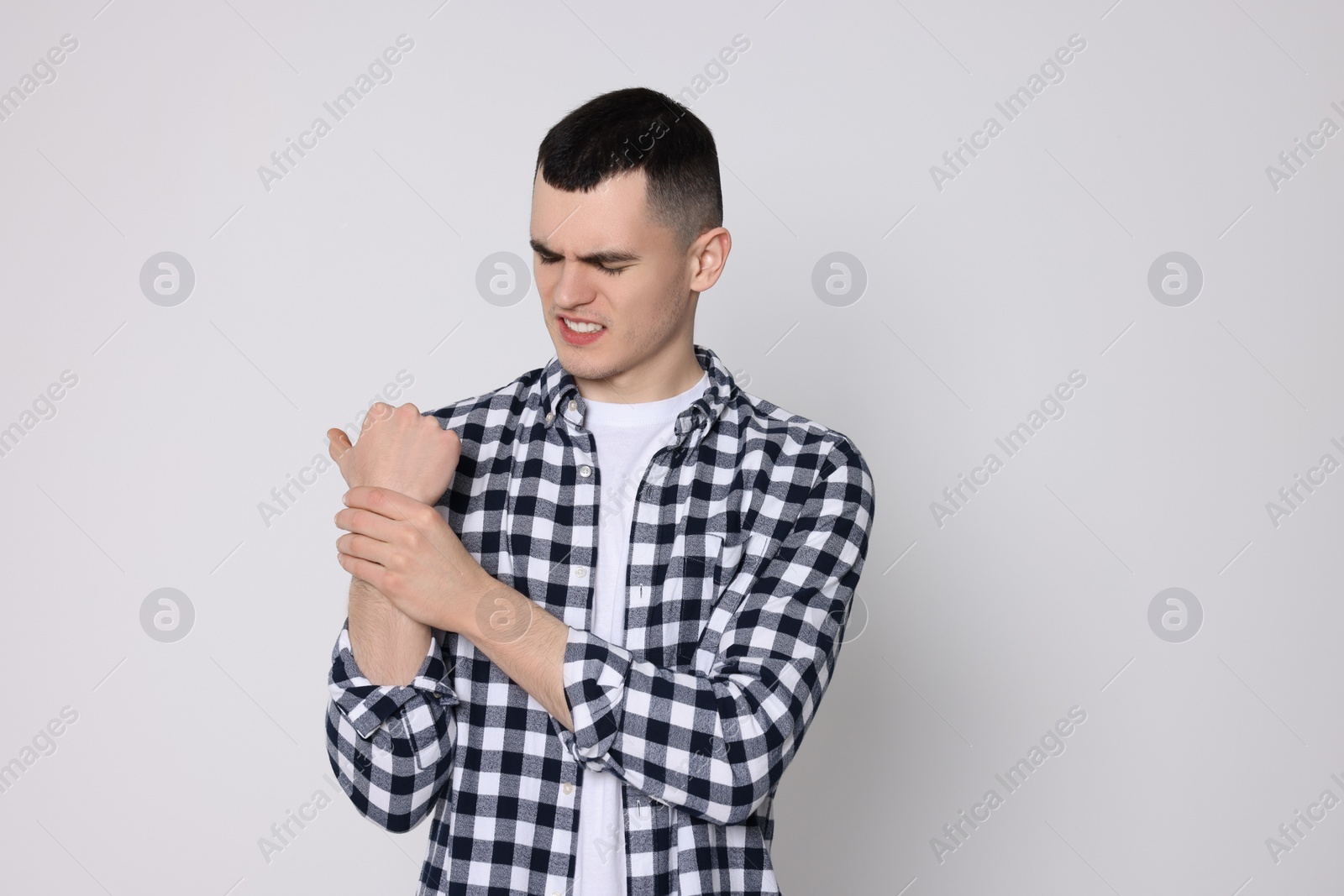 Photo of Man suffering from pain in his hand on light background. Arthritis symptoms