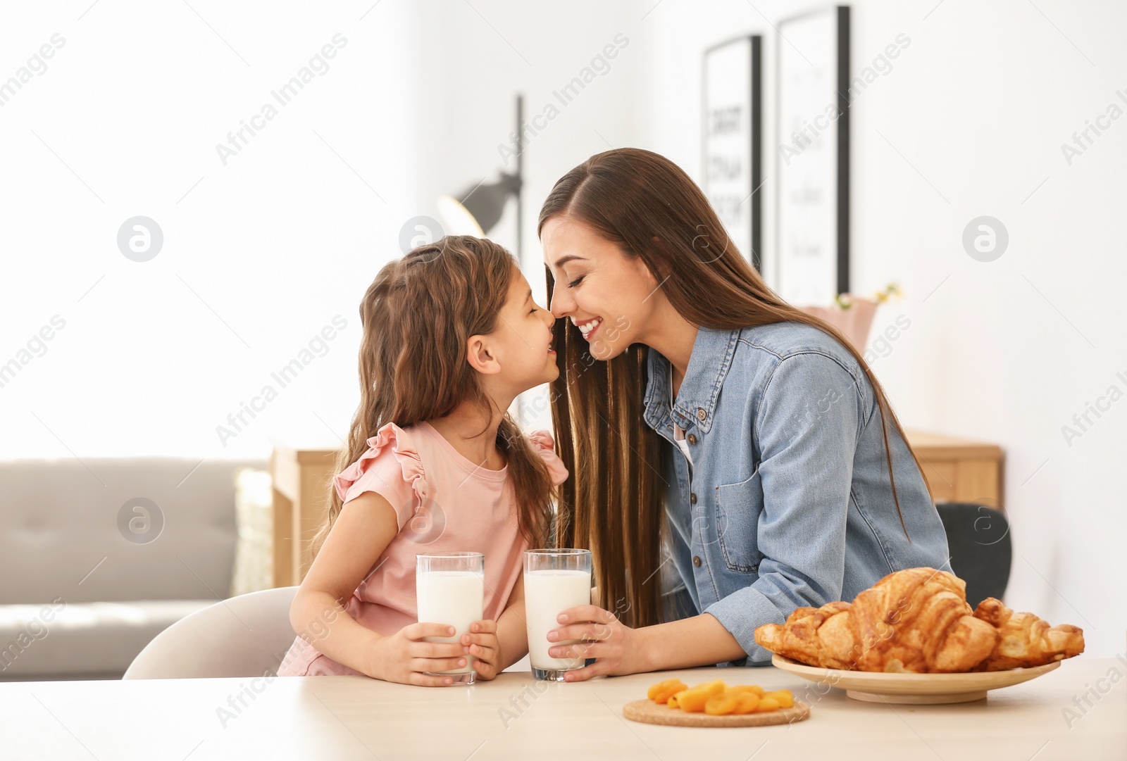 Photo of Mother and daughter having breakfast with milk at table