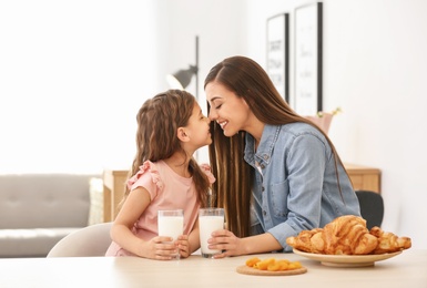 Photo of Mother and daughter having breakfast with milk at table