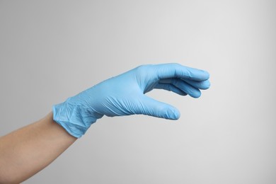 Photo of Doctor wearing light blue medical glove on grey background, closeup