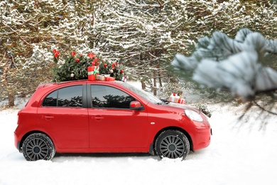 Car with Christmas tree and gifts in snowy forest on winter day