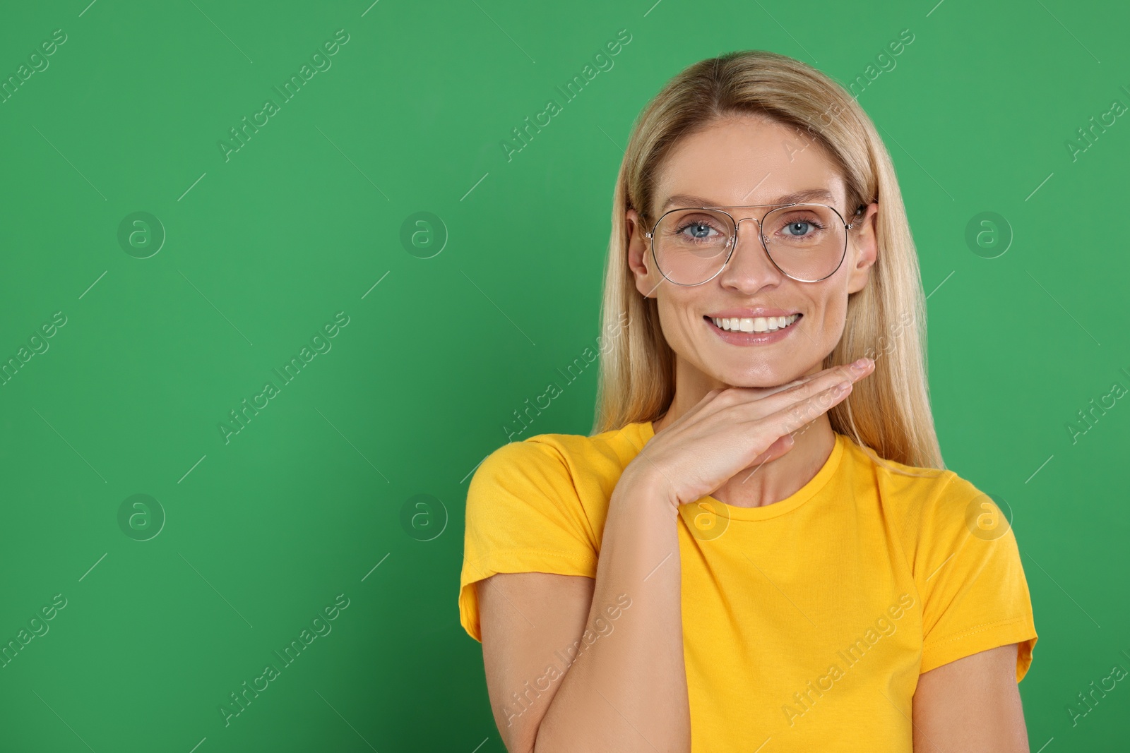 Photo of Portrait of smiling woman in stylish glasses on green background. Space for text