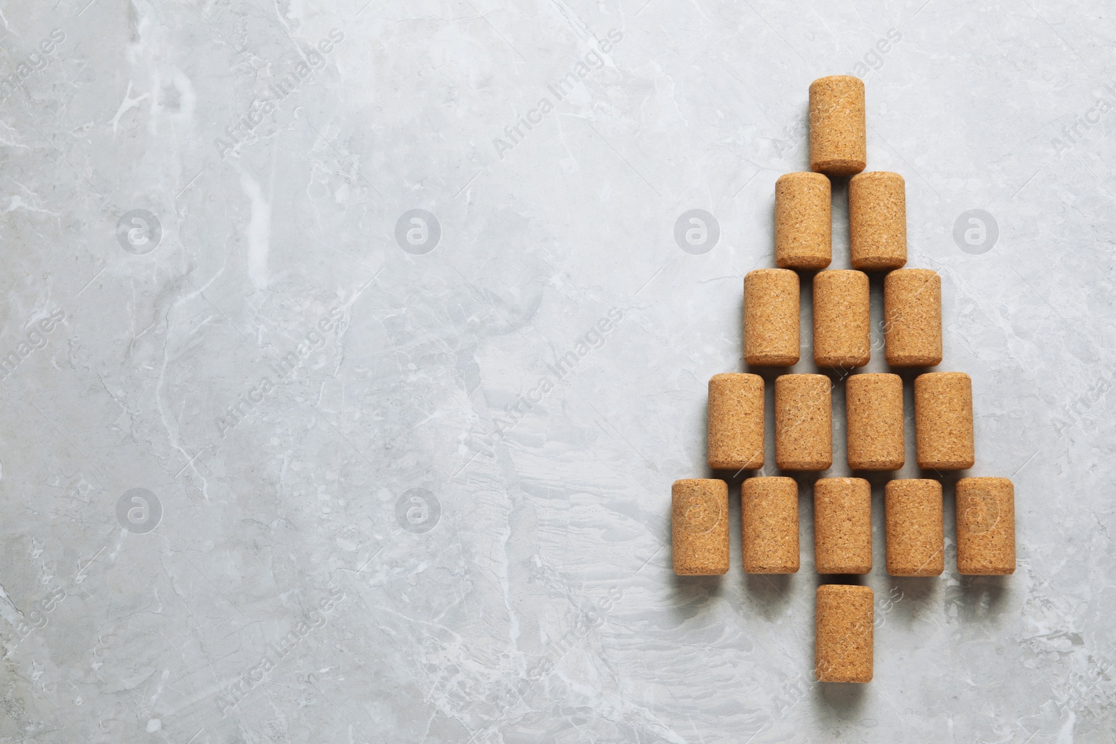 Photo of Christmas tree made of wine corks on light grey table, top view. Space for text