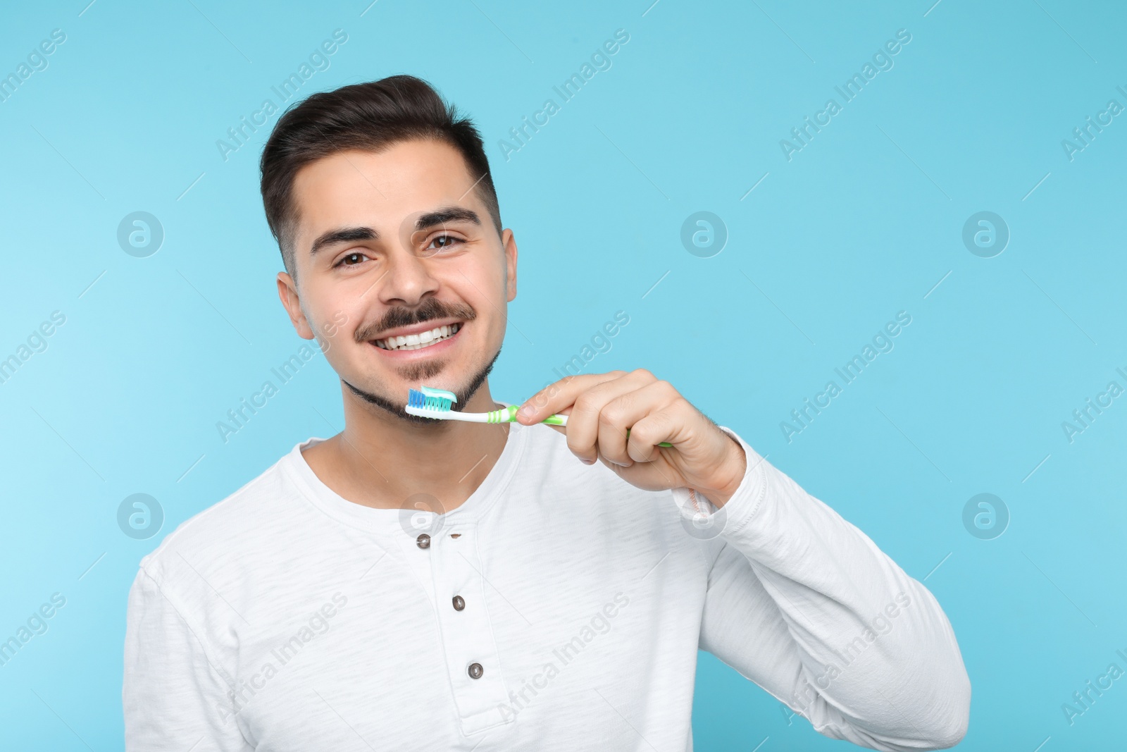 Photo of Young man brushing teeth on color background