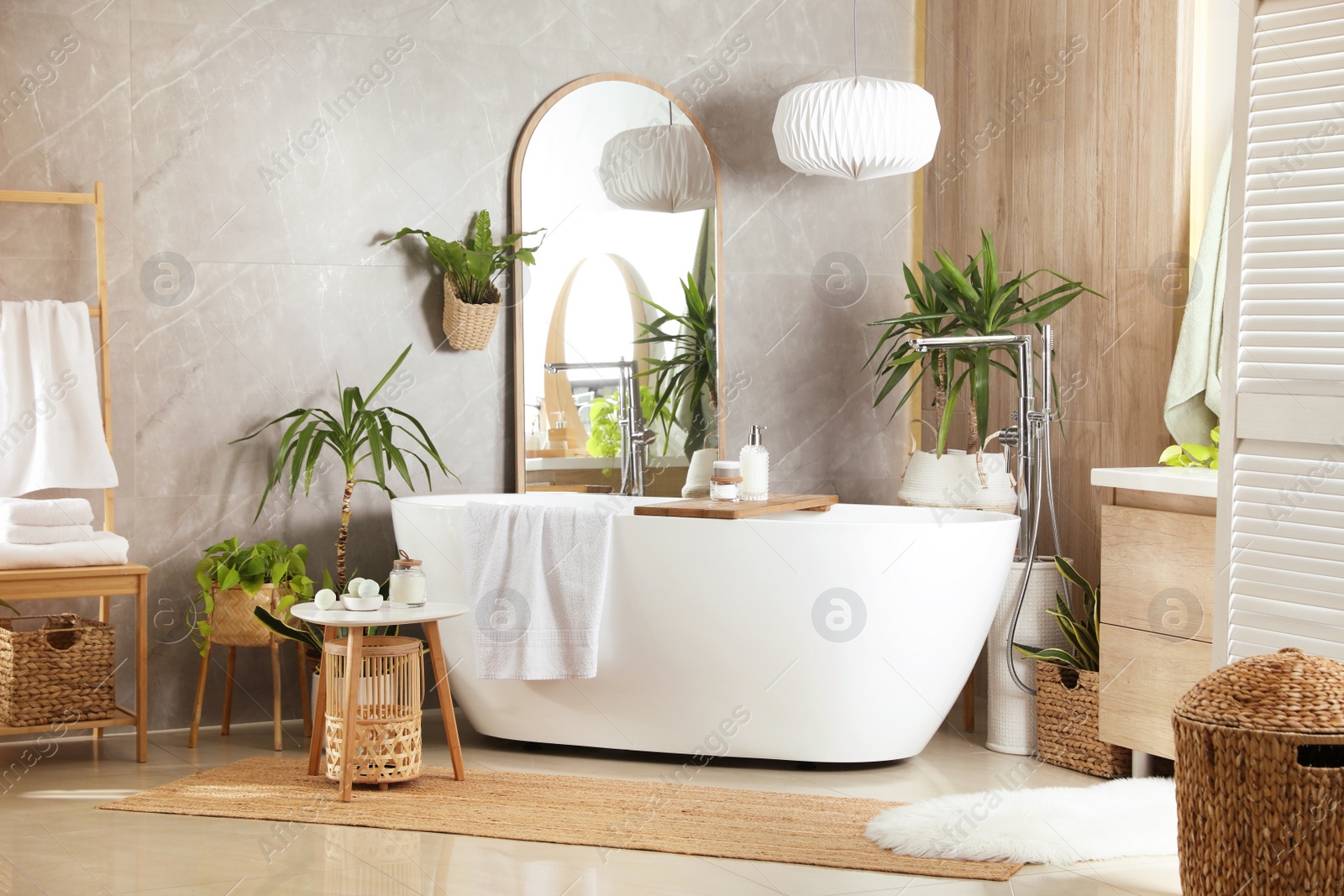 Photo of Modern white tub and beautiful green houseplants in bathroom. Interior design