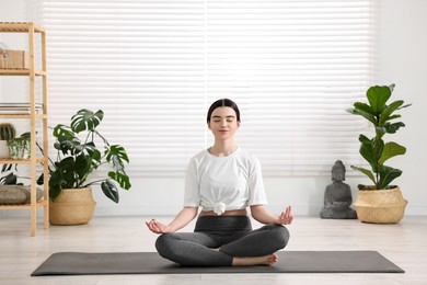 Beautiful girl meditating on mat in yoga studio