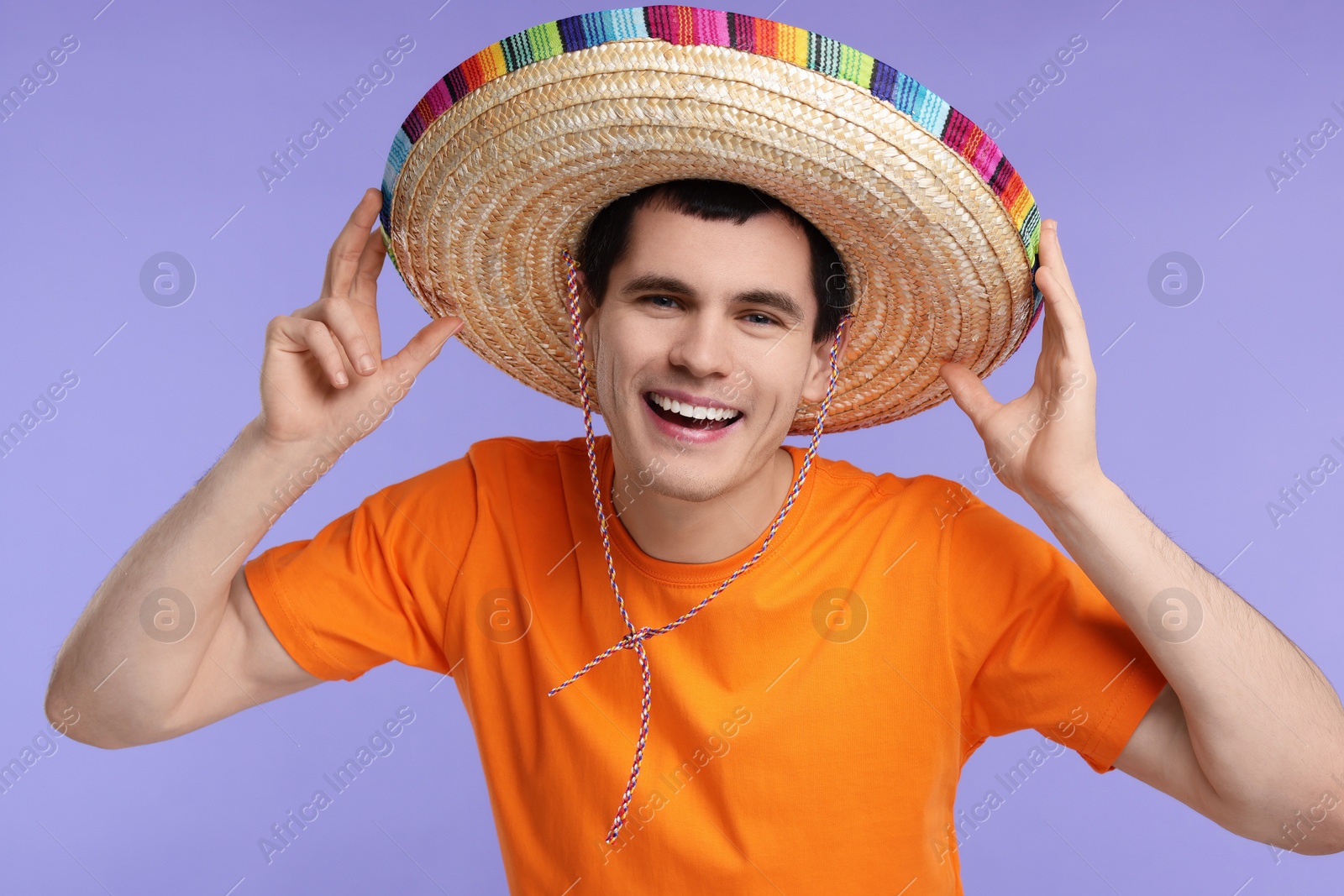 Photo of Young man in Mexican sombrero hat on violet background