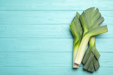 Photo of Fresh raw leeks on blue wooden table, flat lay with space for text. Ripe onion