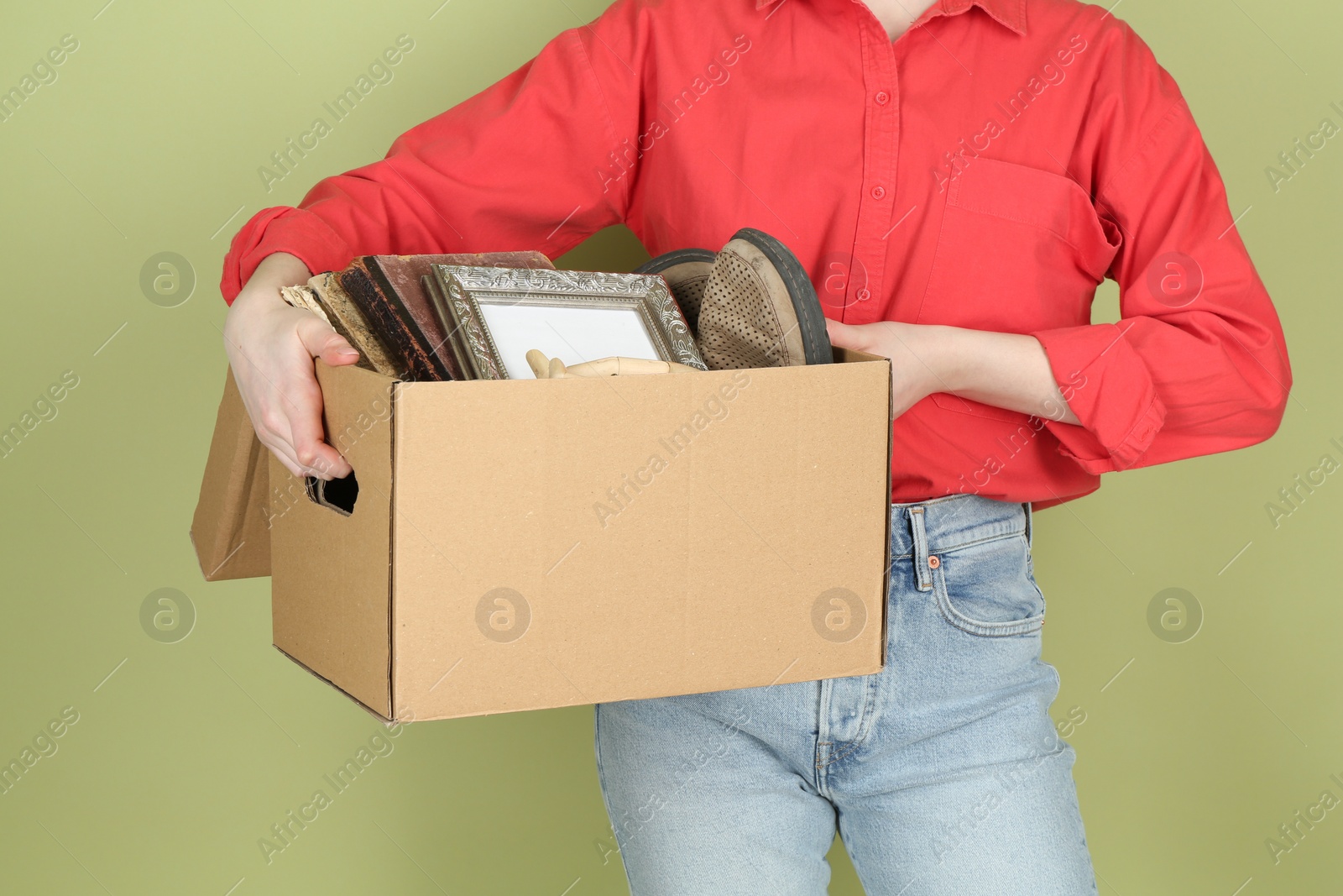 Photo of Woman holding box of unwanted stuff on green background, closeup